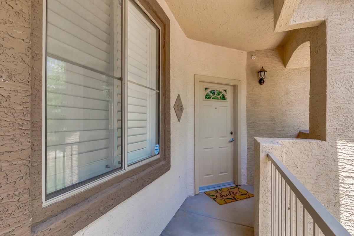 This image spotlights a friendly front door with a welcoming mat, a window, and a light fixture. The scene suggests friendly greetings and the first impressions of coming home, enhanced by soft natural light and inviting decor.