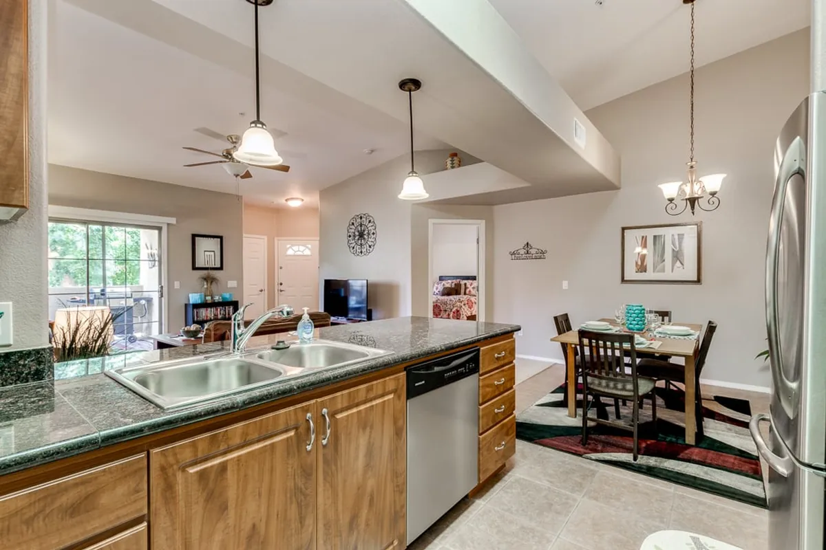 A welcoming kitchen island overlooks a cozy dining area with a view out to the patio. The setup encourages cooking, dining, and entertaining in a bright space that blurs the boundary between kitchen and dining area.