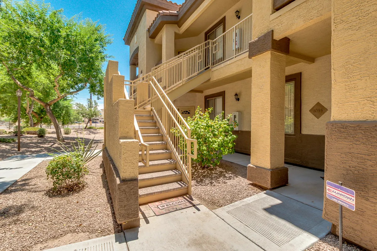 This exterior image shows the entrance to the property, featuring a staircase, a welcoming door, and a landscaped area with greenery. The presence of a welcome mat and well-maintained surroundings immediately conveys a sense of arrival and easy outdoor access, which is ideal for pet owners needing frequent walks.